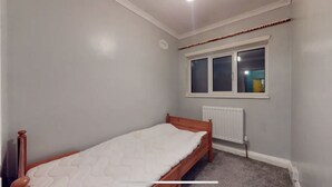 A small, single-bed room with a wooden bed frame, a window with blinds, a radiator, and a ceiling light. - Amazing 4 bed semi-detached house- close to central (London)