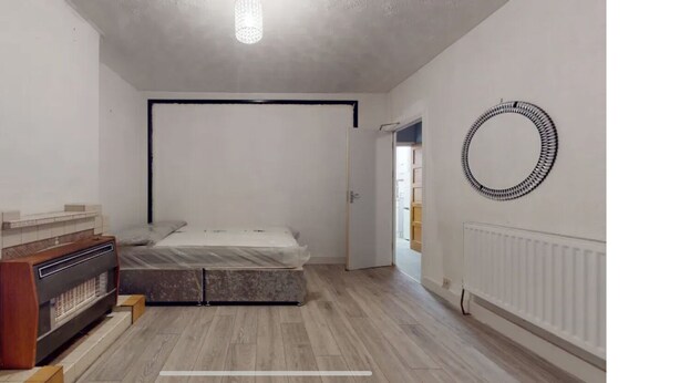 A bedroom with a bed, a radiator, a mirror, and a fireplace. - Amazing 4 bed semi-detached house- close to central (London)