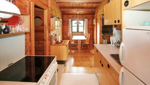 A wooden cabin-style kitchen with a central island, a dining table with chairs, and a refrigerator. - 3 bedroom beautiful home in Samsø (Samsø)