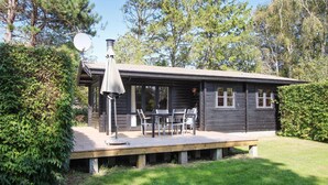 A wooden cabin with a covered patio, outdoor seating, and a satellite dish. - 3 bedroom beautiful home in Samsø (Samsø)