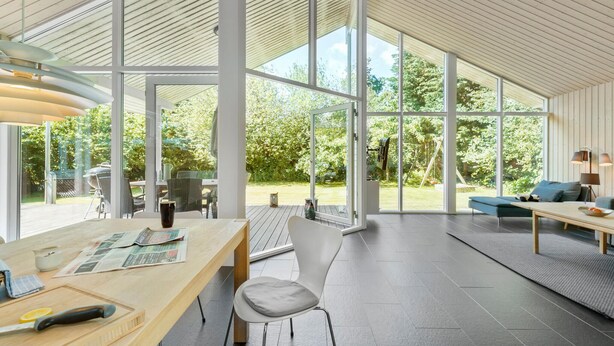 Een ruim, modern interieur met grote ramen, een houten terras en een gezellige zithoek.