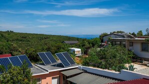 A residential area with solar panels on rooftops, surrounded by greenery and a clear sky. - Awesome apartment in Kavran with WiFi (Kavran)