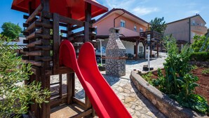 A playground with a red slide and a stone oven structure. - Awesome apartment in Kavran with WiFi (Kavran)