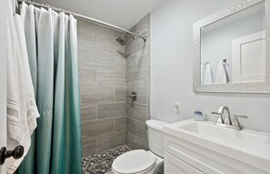 A bathroom with a shower, toilet, sink, and a mirror. - 10 mins walk to train & town, 15 mins walk to lake! (New Buffalo)