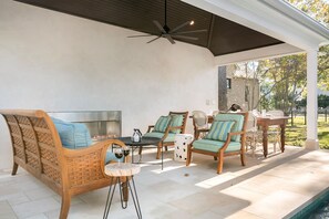 Relax in a stylish outdoor seating area with a sofa, chairs, and a table, surrounded by a garden with trees and a fence.