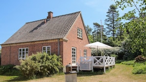 A brick house with a tiled roof, a wooden deck, and a white umbrella. - Cozy home in Samsø with WiFi (Samsø)