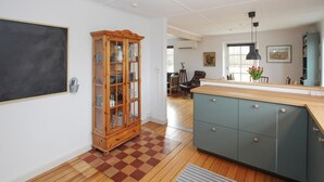 A kitchen with wooden cabinets, a checkered floor, and a large cabinet with glass doors. - Cozy home in Samsø with WiFi (Samsø)