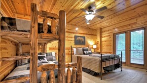 A cabin interior with a bunk bed, a separate bedroom with a bed, a ceiling fan, and a large window.