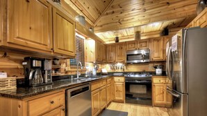 A modern kitchen with wooden cabinets, stainless steel appliances, and granite countertops.