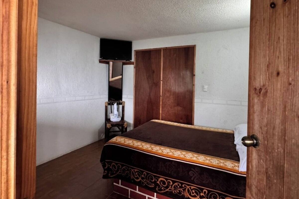 A bedroom with a bed, a wardrobe, and a television on the wall.