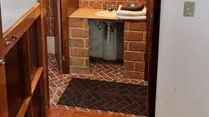 A compact bathroom with a wooden vanity, a mirror, and a sink. - Posada Quetzalin (Cuetzalan del Progreso)