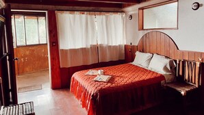 A wooden-paneled bedroom with a bed, a bench, and a window with curtains. - Posada Quetzalin (Cuetzalan del Progreso)