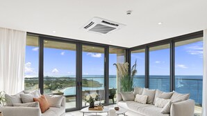 Un salon moderne avec un grand balcon donnant sur une plage et l’océan.