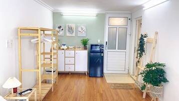 Habitación pequeña con kitchenette, una escalera de madera, una cama y una mesita con lámpara.