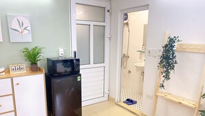 A compact kitchenette with a refrigerator, microwave, and a small clock. - Hanoi Old Quarter Center - 1BR Studio - Big window & Balcony & Private Bathroom (Hà Ni)