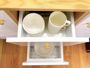 A drawer with white plates, a white bowl, and a white mug.