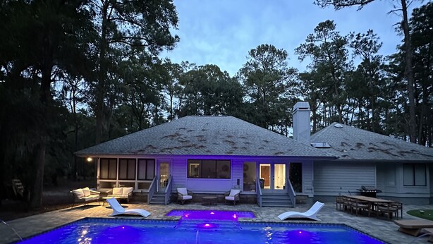 Uma casa com piscina, área de estar externa e varanda coberta.