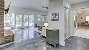 Uma sala de estar ampla com lareira, ventilador de teto e uma área de jantar com mesa e cadeiras.
