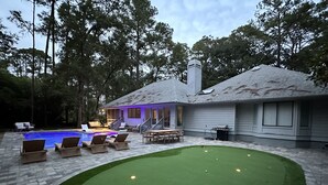 Um quintal com piscina, gramado verde e espaço para churrasco.