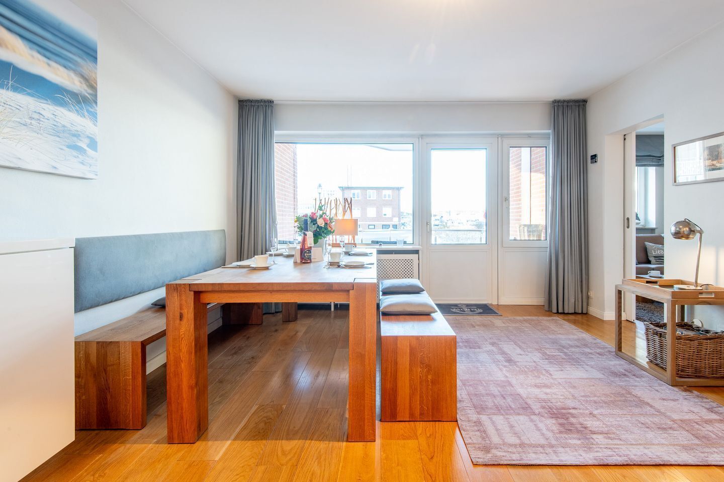 Un salon moderne avec une table à manger en bois, des bancs, une grande fenêtre et une vue sur la ville.