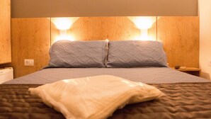 A bed with a quilted headboard, two pillows, and a bedside table with a lamp. - Hotel Descalvado (Descalvado)
