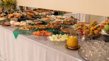 Uma mesa de buffet com diversos alimentos e um jarro de suco de laranja.