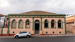 A building with a green and beige facade, arched windows, and a tiled roof. - Hotel Descalvado (Descalvado)