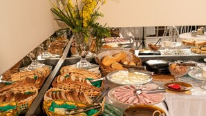A buffet table with various food items and utensils. - Hotel Descalvado (Descalvado)