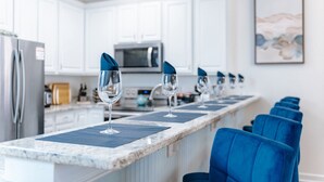 A kitchen with white cabinets, a microwave, and a countertop with blue napkins and wine glasses.