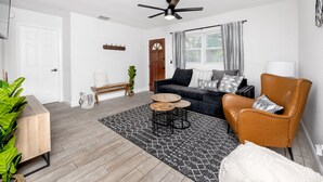 Un salon moderne comprenant un canapé, un fauteuil, une table basse et un ventilateur de plafond.