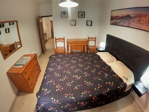 A bedroom with a bed, dresser, desk, chairs, and a mirror. - Algarve, modern T1 apartment with/balcony, Quarteira (Quarteira)