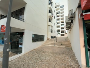 A narrow alleyway with cobblestone pavement, a Speed sign, and a building with multiple balconies and a red awning. - Algarve, modern T1 apartment with/balcony, Quarteira (Quarteira)