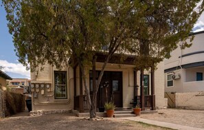 A building with a porch, potted plants, and a brick facade. - Breezy 1BR Retreat • Walk to UofA (Tucson)