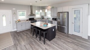 A modern kitchen with a central island, stainless steel appliances, and light gray cabinetry. - Dockside - Picture Perfect Home - Gorgeous Views! (Arapahoe)