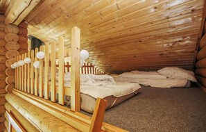 A cozy cabin room with a wooden ceiling, a bunk bed, and a small window.
