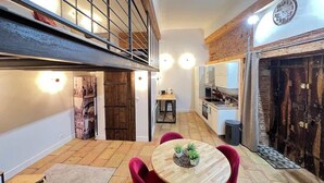 A spacious living area with a high ceiling, a fireplace, and a dining table with chairs. - La Romance - Loft Ancien au coeur de Toulouse (Toulouse)