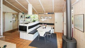 A compact kitchen with a central island, a dining area with chairs, a stove, and a map on the wall. - 2 bedroom lovely home in Samsø (Samsø)