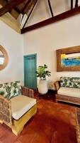 Una sala de estar acogedora con muebles de mimbre, una planta en maceta y un cuadro en la pared.