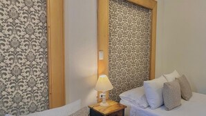 A hotel room with two beds, a nightstand with a lamp, and patterned wallpaper. - Camino a Santa Fe (Guaduas)