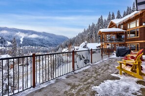 A wooden chalet with a balcony overlooking a snowy mountain landscape.