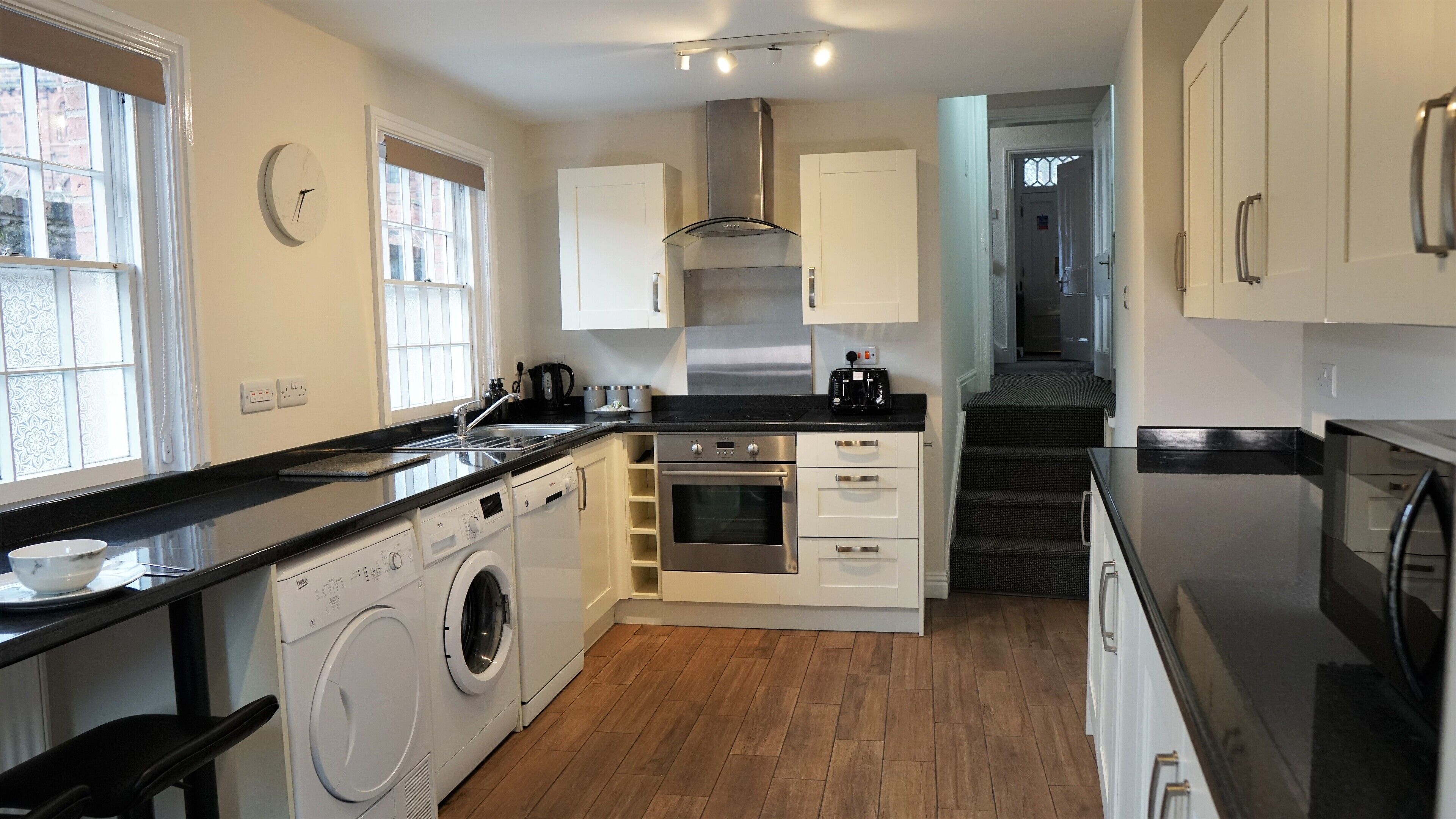 A modern kitchen with a washing machine, oven, and stainless steel appliances.