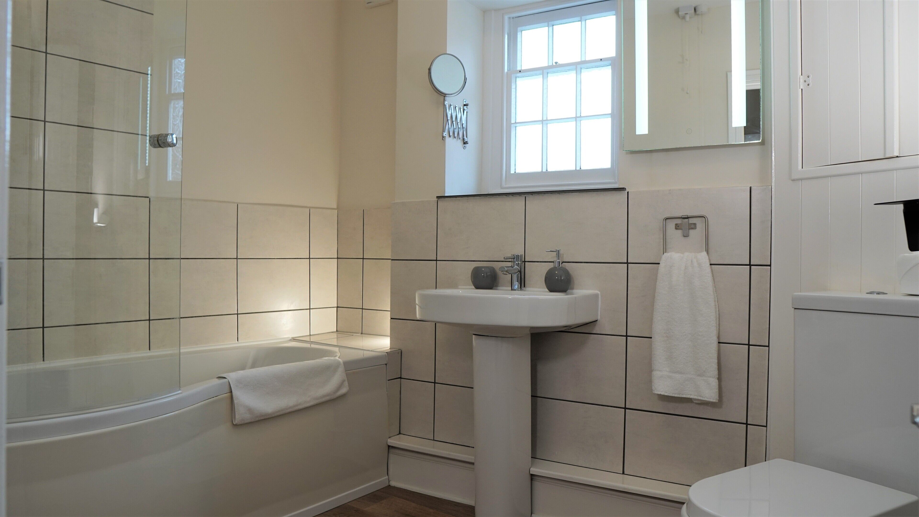 A bathroom with a bathtub, a sink, a toilet, and a window.