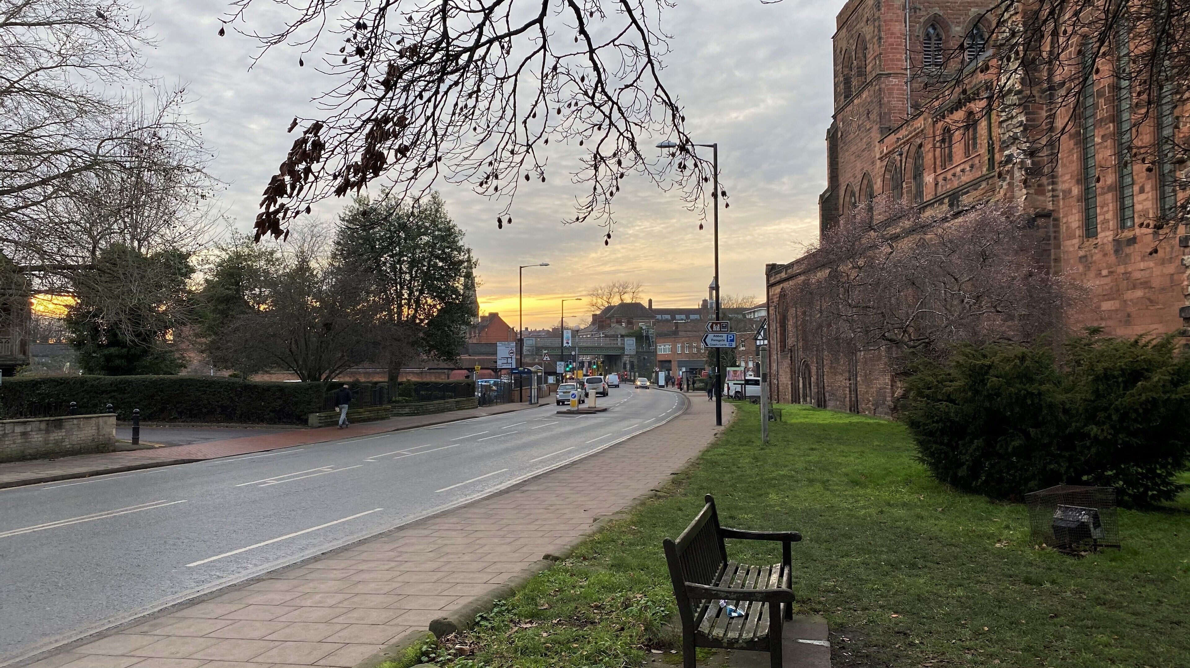 A street with a bench, a building, and a clear sky.