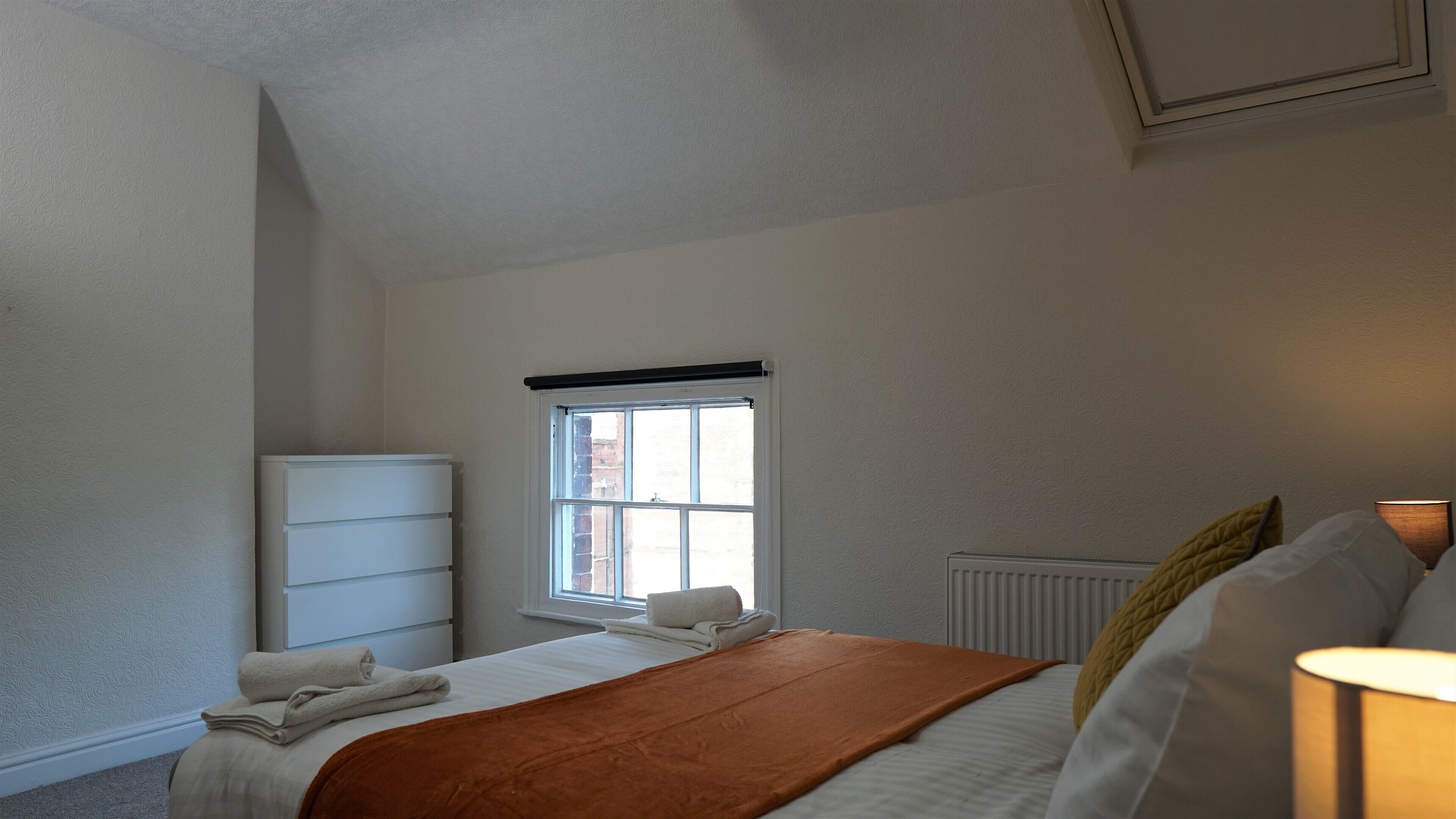 Ein Schlafzimmer mit Bett, Heizkörper, Fenster und Kleiderschrank.