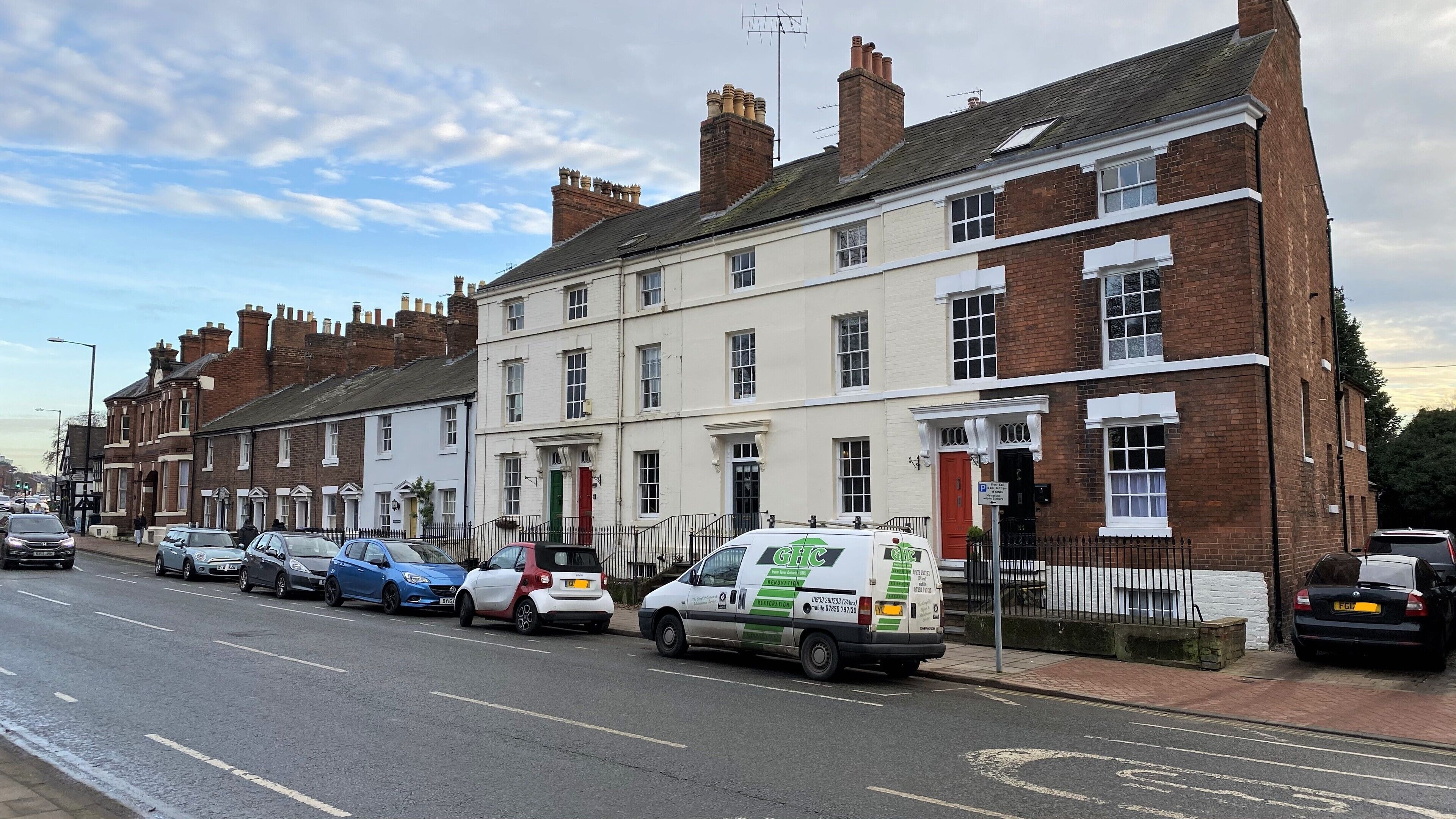A row of terraced houses with a white van parked on the street.