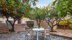 Un espace extérieur aménagé avec une table et des chaises, entouré d’arbres chargés de fruits.