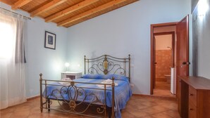 Une chambre à coucher avec un lit, une table de chevet, une armoire en bois et une porte menant à la salle de bain.
