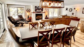 Un salón amplio con un sofá seccional grande, una mesa de comedor con sillas y una chimenea.