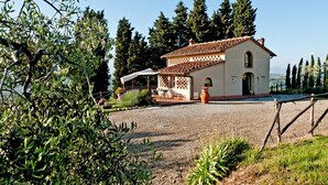 Una villa rústica con techo de tejas, un porche cubierto y un camino de entrada de grava.