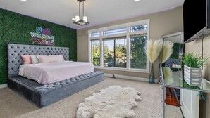 A bedroom with a tufted headboard, a bed with pink bedding, a white fur rug, and a neon sign. - Welcome To Your New Favorite Spot! Tree Top Views & Lots Of Room! (Salem)